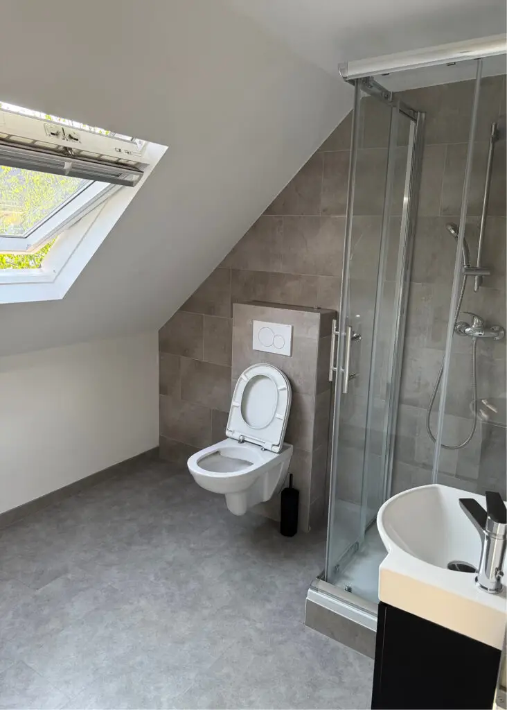 Salle de bain moderne sous comble avec fenêtre de toit.