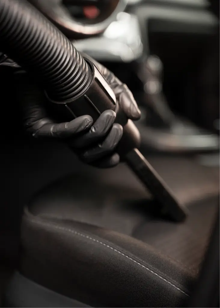 Nettoyage professionnel de l'intérieur d'une voiture avec un aspirateur.